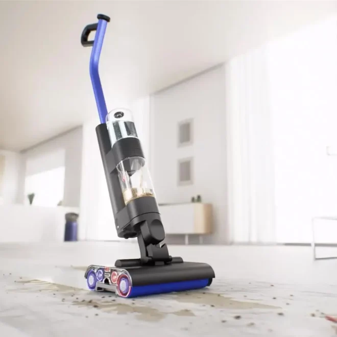 Dyson Wash G1 mokrý čistič podlah zachycený při úklidu rozlité tekutiny na světlé podlaze v moderní domácnosti.