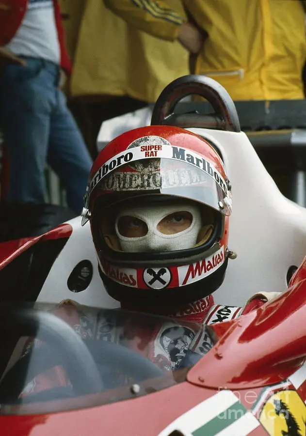 Niki Lauda s nasazenou helmou a kuklou během Velké ceny Rakouska 1977, sedí připraven ve svém závodním voze Ferrari.