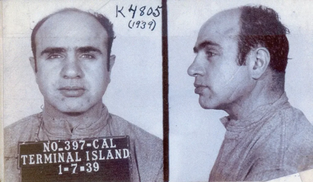 Mugshot fotografie Al Capona z roku 1939 pořízená ve věznici Terminal Island, zobrazující pohled zepředu i z profilu.