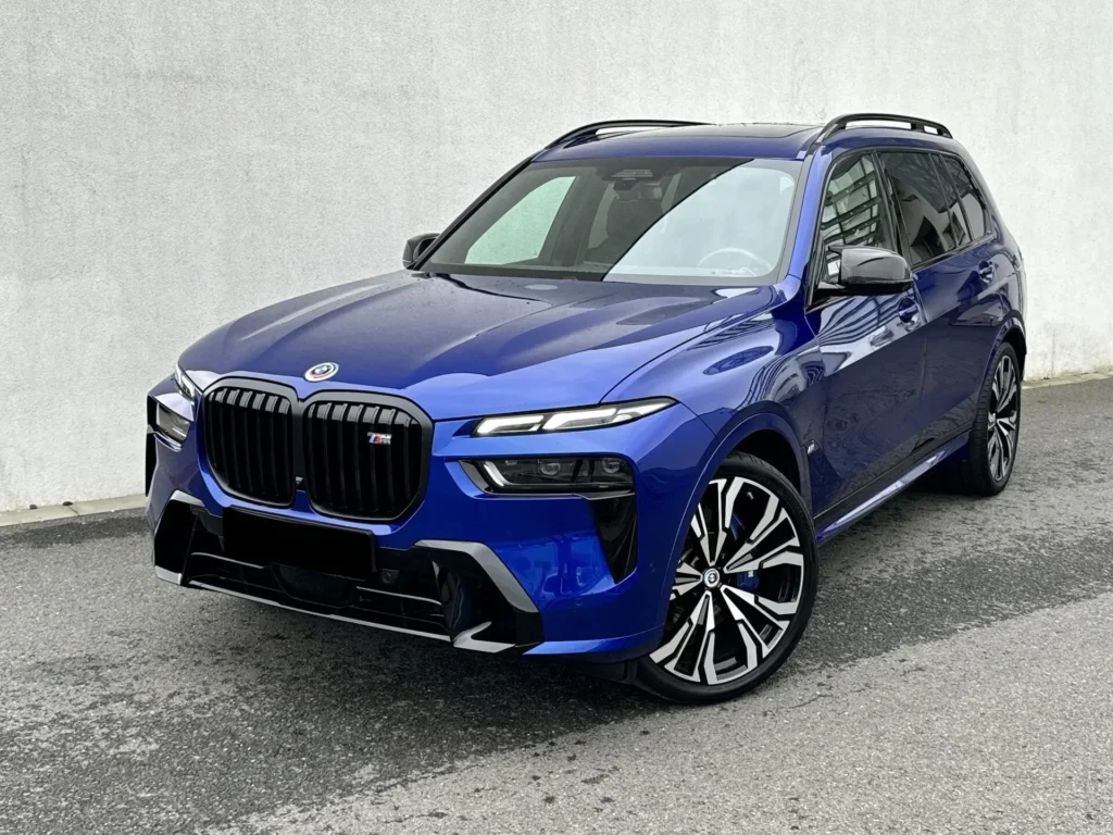 Modré BMW X7 zaparkované na ulici, detailní pohled na jeho masivní přední masku, moderní design a sportovní kola.