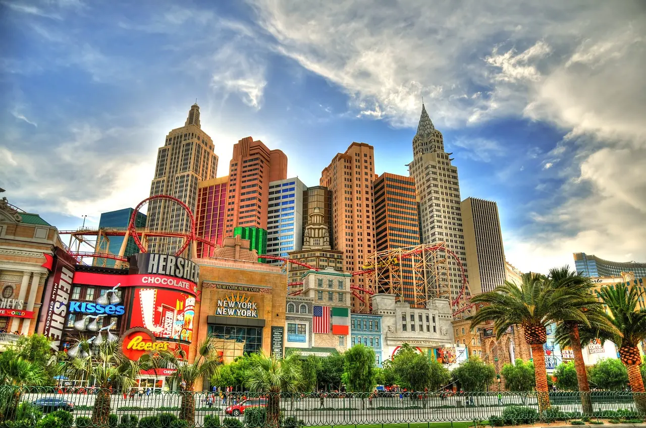 Ikonická část Las Vegas Strip s neonovými světly, hotely a rušným městským životem, zachycená za jasného dne.