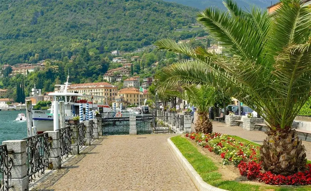 Promenáda u Lago di Como lemovaná palmami a malebnými budovami.