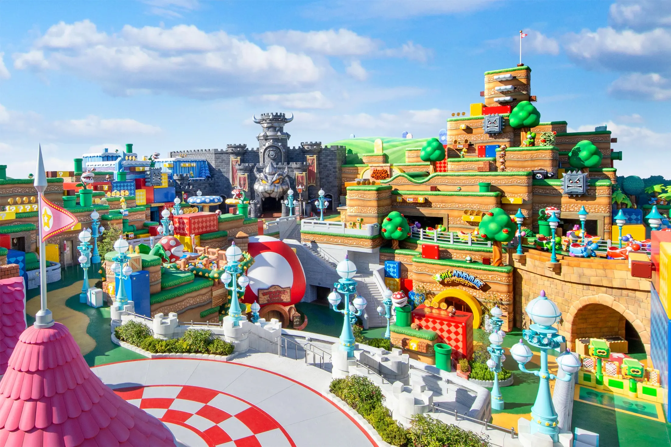 Barevný herní svět Super Nintendo World v Japonsku s ikonickými prvky Maria, Yoshim, kostkami s otazníkem a Bowserovým hradem na pozadí.