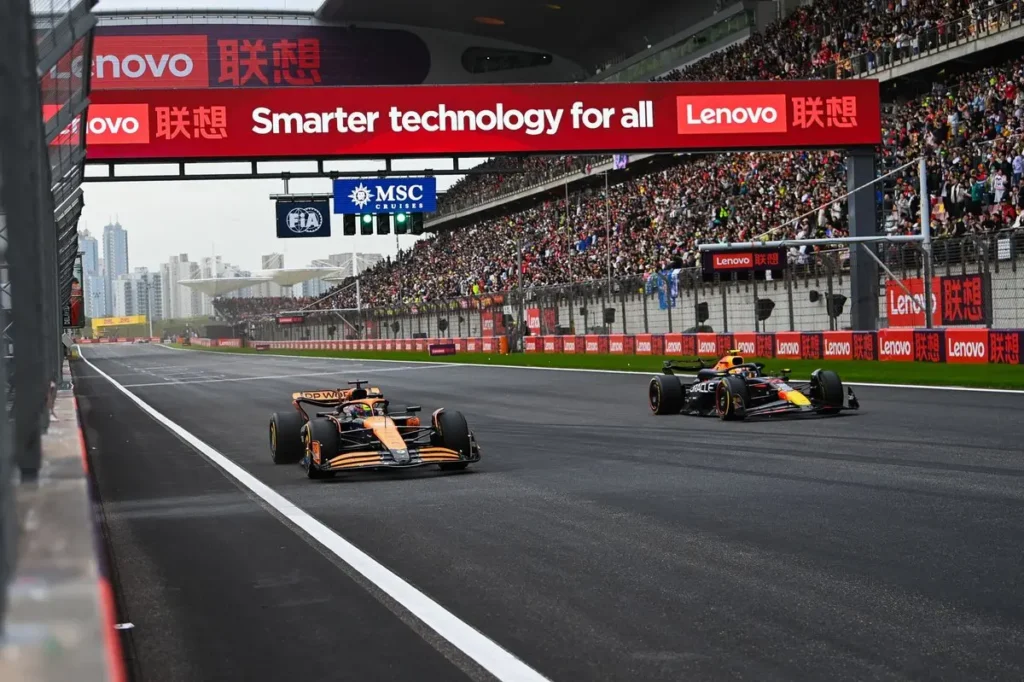 Závodní vozy Formule 1 projíždějí cílovou rovinkou okruhu Shanghai International Circuit za podpory zaplněných tribun během Velké ceny Číny.