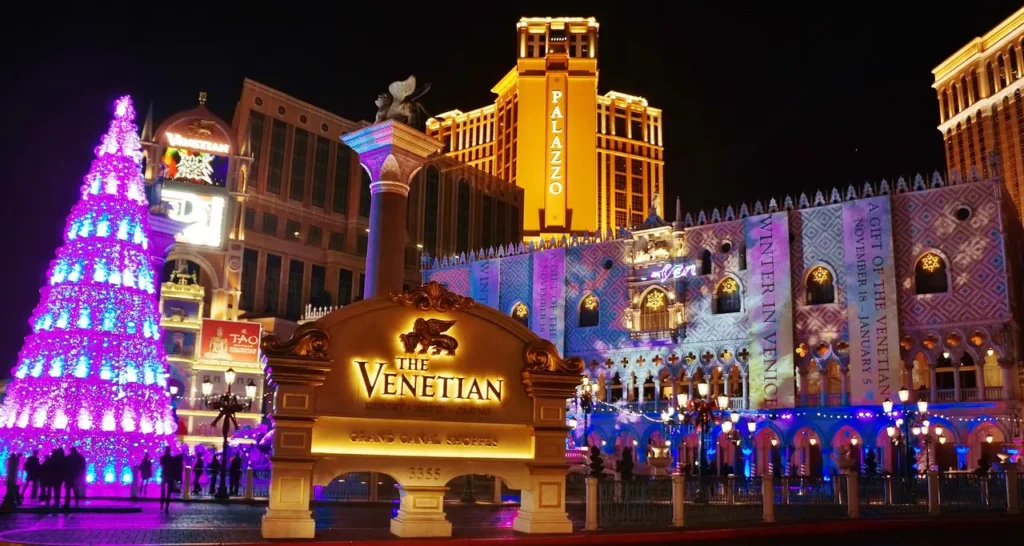 Noční pohled na resort Venetian v Las Vegas s vánoční výzdobou a nasvícenou dominantou v pozadí.