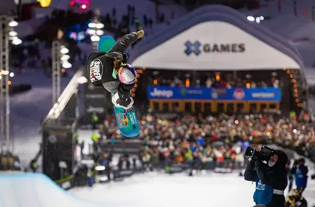 Snowboardová exhibice na Winter X Games s diváky a atmosférou noční soutěže.