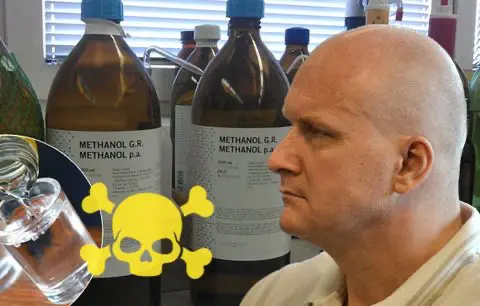 Obviněný v metanolové kauze před lahvemi označenými „Methanol G.R.“, symbol lebky s kostmi upozorňuje na jedovatost látky.