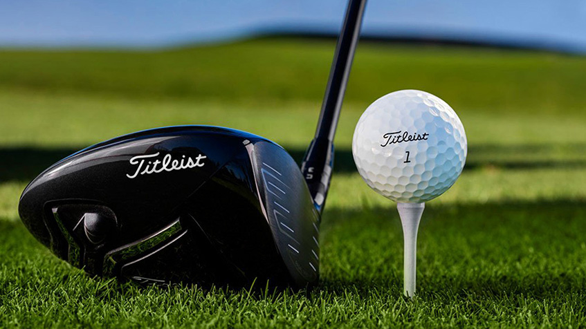 Golfová hůl Titleist spolu s golfovým míčkem Titleist umístěným na odpališti, připravené k úderu na zeleném trávníku