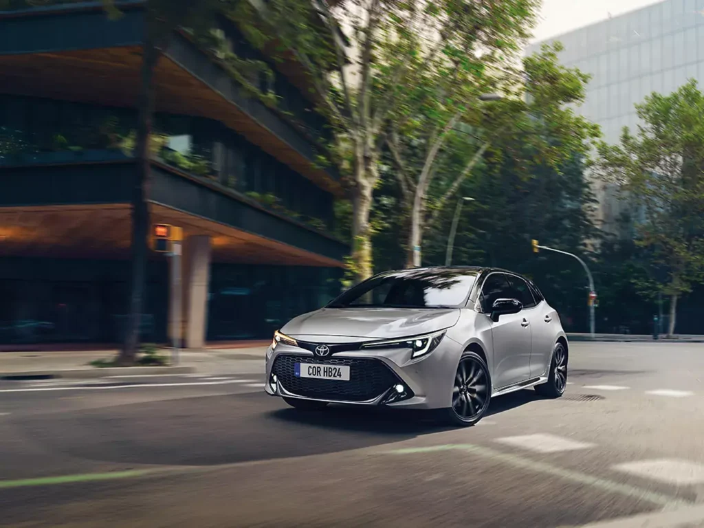 Toyota Corolla Hatchback projíždějící městem, elegantní křivky a sportovní silueta ve městském prostředí.