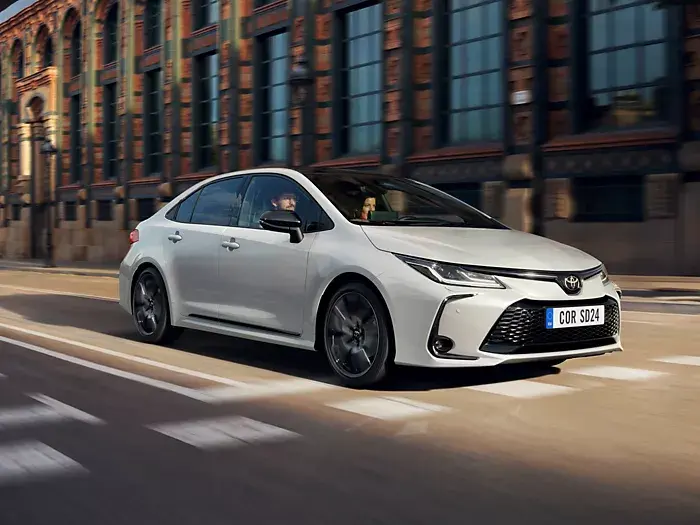 Toyota Corolla Sedan v pohybu na městské ulici, aerodynamický design a ikonický styl.