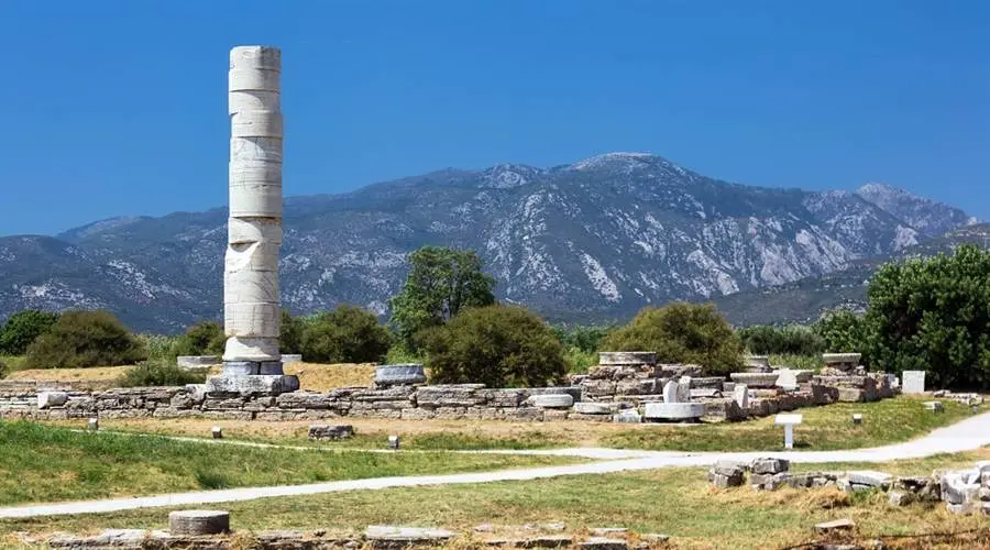 Ruiny starověkého chrámu Heraion na ostrově Samos s jedním dochovaným sloupem a horami v pozadí za jasného dne.