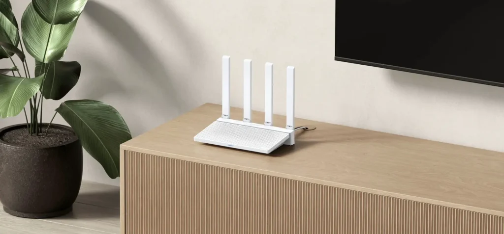 Bílý WiFi router se čtyřmi anténami umístěný na dřevěné skříňce vedle zelené rostliny v květináči, v moderním interiéru s minimalistickým designem.