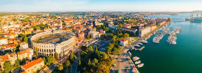 Letecký pohled na chorvatské město Pula s římským amfiteátrem a přístavem u Jaderského moře.