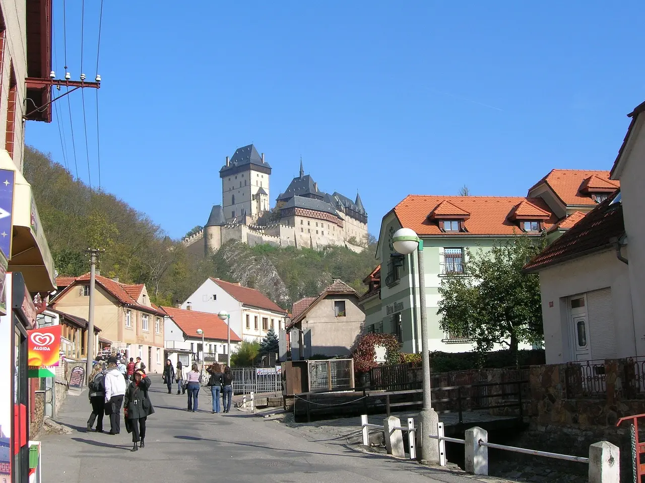 Pohled na hrad Karlštejn z nedaleké vesnice, kde se historická architektura prolíná s každodenním životem.